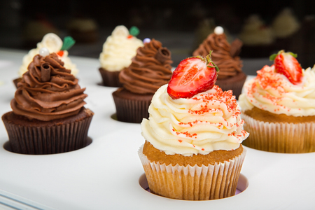 colorful cupcakes with different Tastes. Small beautifull chocolate and strawberry cupcakes on white Shop-window.の写真素材