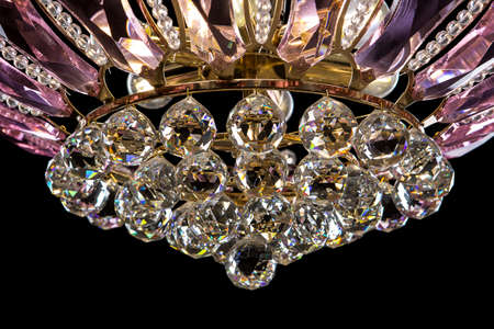 Contemporary gold chandelier isolated on black background. Crystal chandelier decorated Pink crystals close-upの写真素材