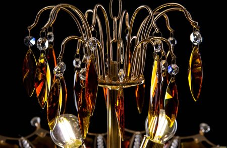 Contemporary gold chandelier isolated on black background. Crystal chandelier decorated amber crystals close-upの写真素材