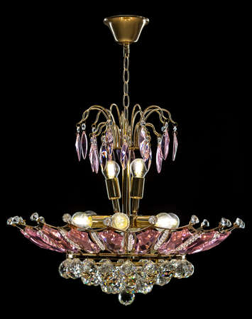 Contemporary gold chandelier isolated on black background. Crystal chandelier decorated Pink crystalsの写真素材