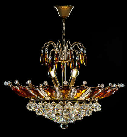 Contemporary gold chandelier isolated on black background. Crystal chandelier decorated amber crystals.の写真素材