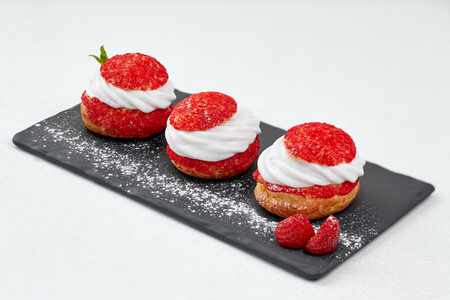 French Cakes with strawberry cream shanti. aery Strawberry brewing cake on black shale. Restaurant...