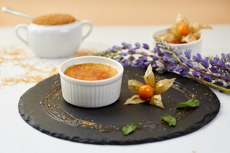 Creme brulee with Physalis and brown sugar. Creme brulee dessert with lavender and coffee on black shale.の写真素材