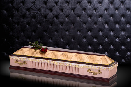 closed wooden beige coffin with red roses covered with cloth isolated on gray luxury background. casket with shadow.の写真素材