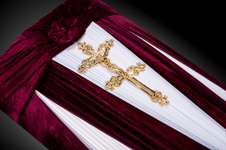 closed red velvet coffin covered with cloth isolated on gray background. coffin close-up with gold Church cross.の写真素材