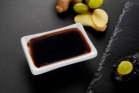 Fresh ginger with a grape, soy sauce for sushi. Black shale background.の写真素材