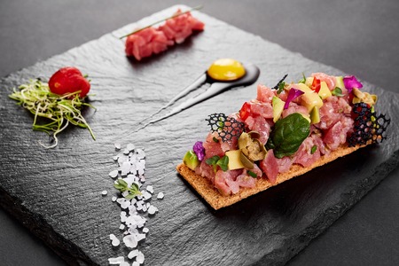 fresh tuna tartar with salt and herbs, studio shot. Fish tartar on black shale.の写真素材