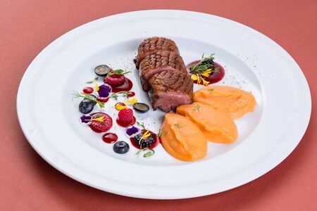 fried meat served with berries and pumpkin puree.の写真素材