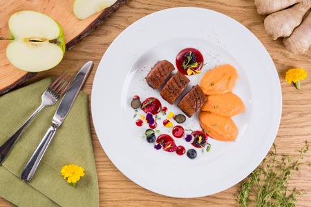 fried meat served with berries and pumpkin puree.の写真素材