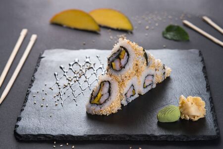 california roll with sesame. Roll with shrimp and mango. Japanese food. Roll on a black shale with...