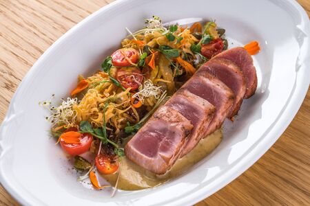 Tagliata of tuna with vegetable spaghetti. Fried tuna with garnish on a white plate. Appetizer plate. Fish dish Italian cuisineの写真素材