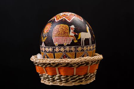 One large Pysanka, decorated Easter egg in basket on black background.の写真素材