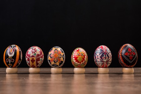 Pysankas in a row, decorated Easter eggs on black background.