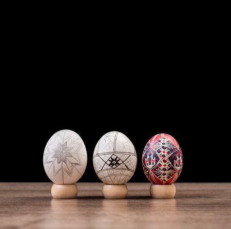 Three Pysankas in a row, decorated Easter eggs on black background. Easter egg at different stages...