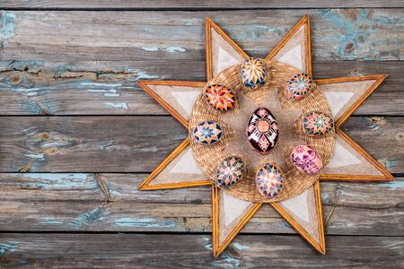 Pisanky and ethnic star frame on a wooden background. Easter eggs on a wooden table. Painted eggs for Easter holidays.の写真素材
