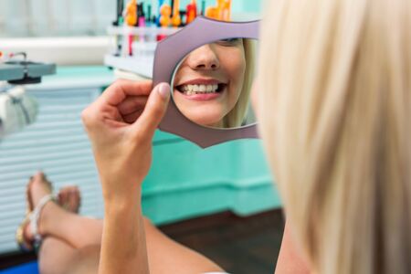 Woman checking teeth in mirror. Female at the dentist office.の写真素材