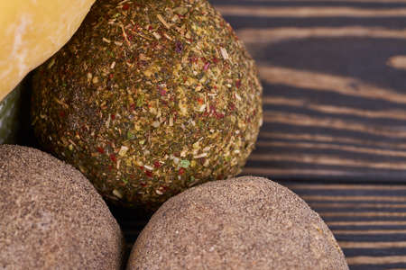 Round heads of rustic natural cheese with sice lie on a wooden board.