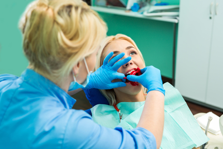 female dentist treating patient girl teeth. Young blonde girl sitting at the dentistの写真素材