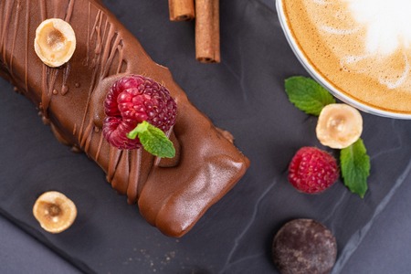 Top view of caramel chocolate cake with hazelnuts. Served with cinnamon, raspberries and mint on black background.の写真素材