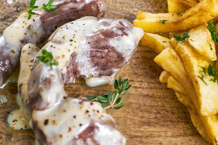 Grilled veal with french fries served with sauce on glass plate. Closeup view.の写真素材
