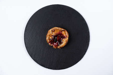 Fruit bun with honey on round black rock stand on white background. Puff with fruit and honey in cafe. View from above. Tasty dessert concept. Sweets to order concept. Round cake on slate stand.の写真素材