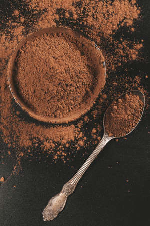 Cocoa powder in bowl and spoon on dark background, top viewの写真素材