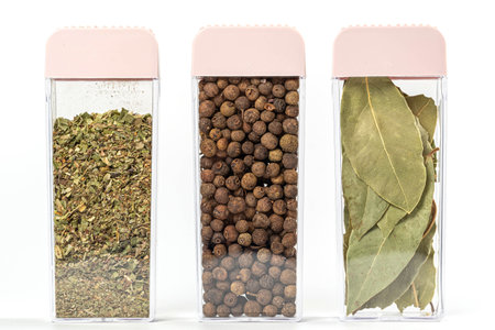 Dried Italian herbs, allspice and bay leaves in containers on whiteの写真素材