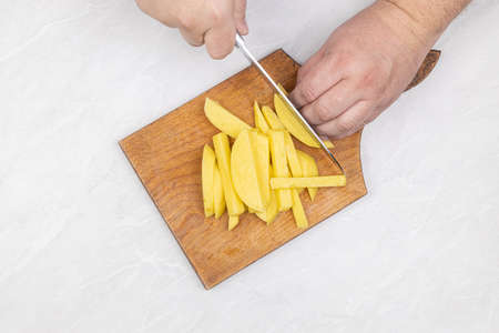 Top view of sliced raw potatoes on the wooden cutting boardの写真素材