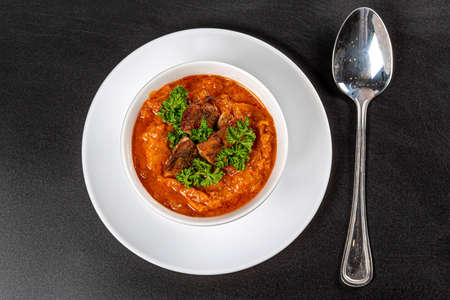 Vegetable soup with carrots, zucchini, chicken fillet and green parsley on a black background, top viewの写真素材
