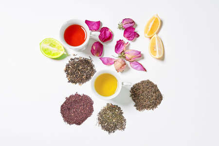 Refreshing tea cups on white with dry tea leafs and fruits