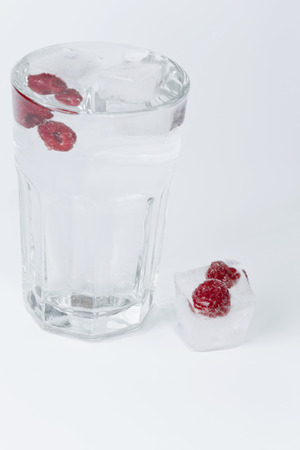glass of water ice raspberries on a white backgroundの写真素材