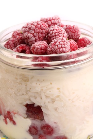breakfast rice porridge with vanilla sauce, frozen raspberries in a glass jar white backgroundの写真素材