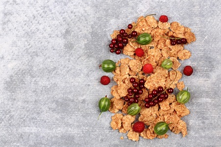 breakfast corn flakes with fresh berries on a stone background