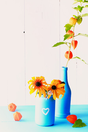 Autumn rural Community Decor handmade glass jar and a bottle of colored paint with autumn flowers on a wooden backgroundの写真素材