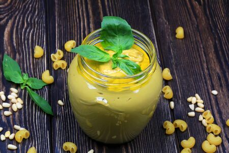 Pesto sauce for pasta on a dark wooden background. Cedar nuts, basil, garlic, olive oil, cheese