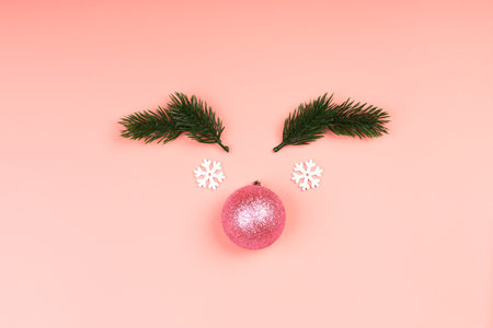 Creative christmas minimalistic composition. Christmas ball on a pink background. pink glitter christmas toy with christmas tree branches. top view, flat style, empty place for textの写真素材