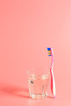 toothbrush and a glass of water on a pink backgroundの写真素材