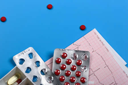 Medical cardiology concept. Heart health pills and cardiogram on a blue background. ECG. Copy space.の写真素材
