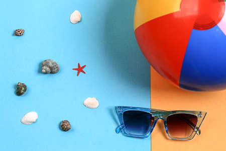 summer sunglasses on bright yellow-blue background with inflatable multicolored beach ball