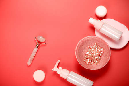 Cosmetic concept. Facial care cosmetics on a pink background. Cleansing & Moisturizing Gel, Facial Roller Massager & Anti-Aging Capsulesの写真素材