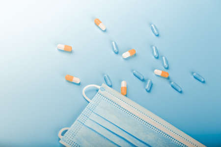 Medical background. Pills and medical mask on a blue background.の写真素材