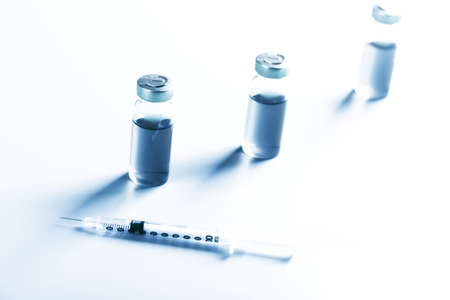vaccine bottles on a blue background. medical concept. Very shallow depth of field. illumination across the frameの写真素材