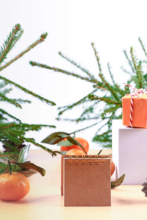 Christmas composition with spruce, tangerines, podium and notepad. Soft selective focus. Winter festive backgroundの写真素材