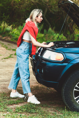 girl looks under the hood of a broken car. Soft selective focus