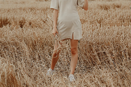 young woman stands in a field with wheat.の写真素材