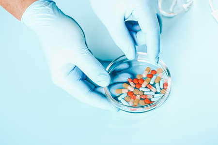 Abstract medical background. doctors hands in medical gloves hold multicolored pillsの写真素材