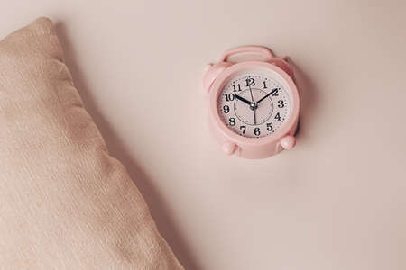 Pillow and alarm clock on a beige background. Healthy restful sleep concept.の写真素材