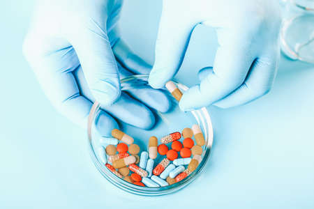 Abstract medical background. doctors hands in medical gloves hold multicolored pillsの写真素材