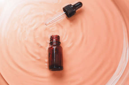 Abstract cosmetic laboratory. Bottles of dark amber glass on a beige liquid background. Natural...