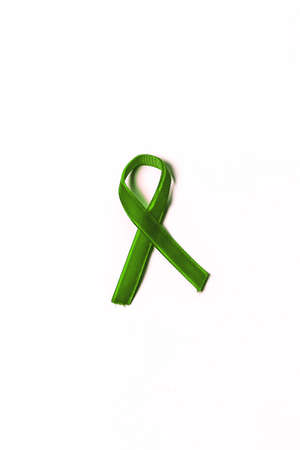 Green velvet ribbon on white background. World Mental Health Day. Cancer Awareness Symbolic Ribbon.の写真素材